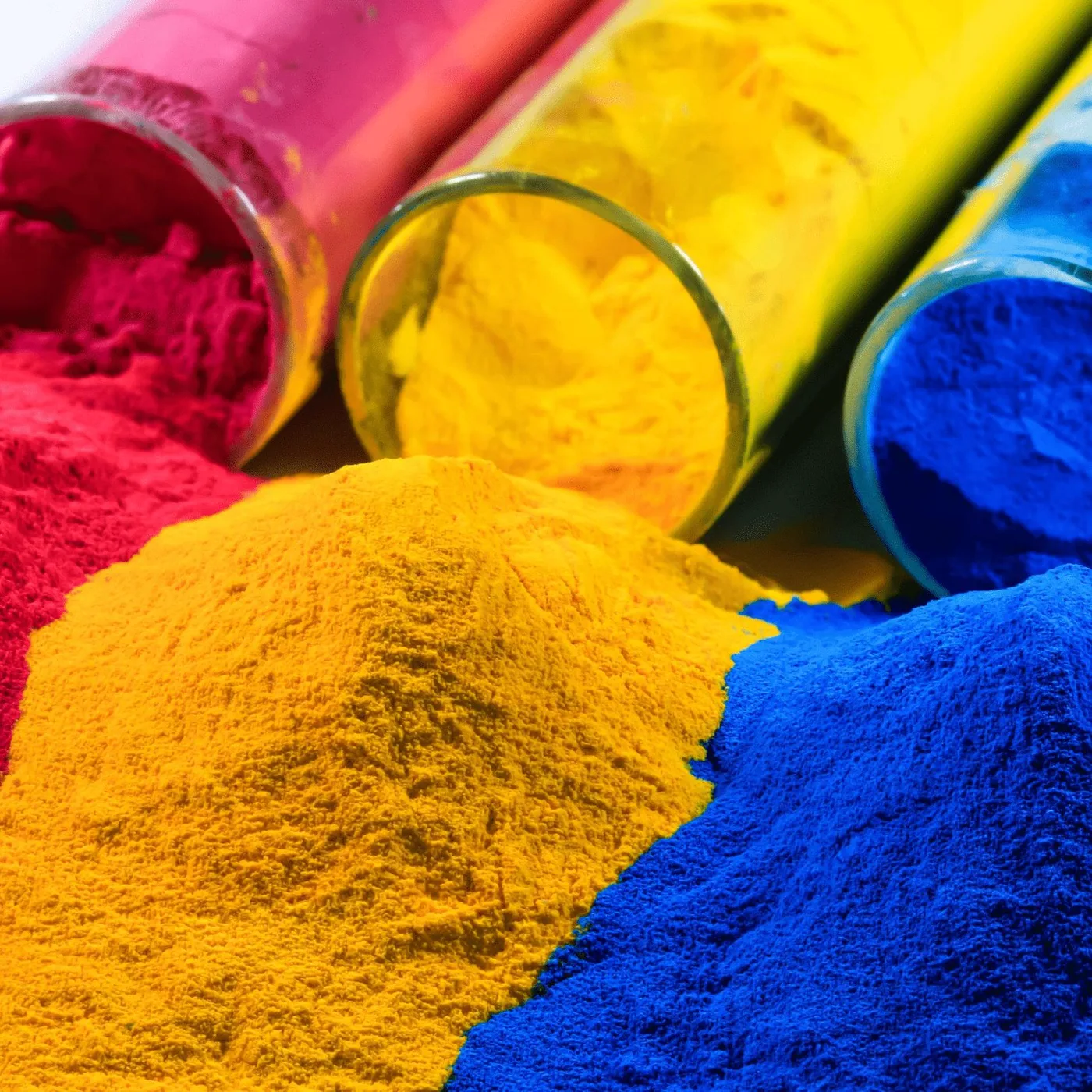 Containers of pink, yellow and blue powder coating pigment tipped onto a bench